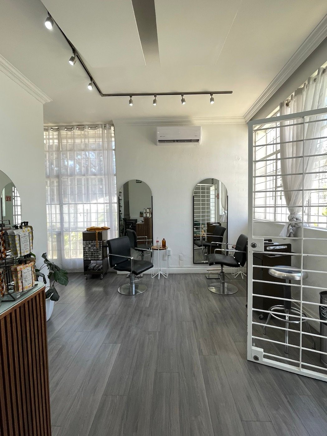 Salón blanco con espejos de arco y piso de madera